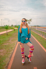 mujer hermosa con medias altas y patines al aire libre sonriendo con unas gafas de sol 