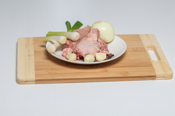Chicken with vegetables on a white plate is ready for cooking soup.