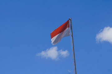indonesian national flag flutter on flagepole at daylight with blue skya and cloud