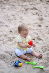 little boy playing in the sand. baby plays with sand. Summer rest. Sun, sea, beach, sand. Rest, childhood.