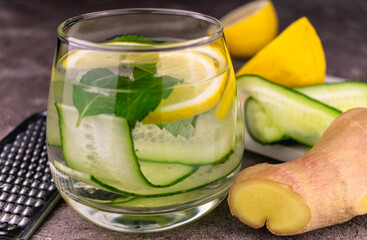 Fresh cold water with lemon, cucumber, ginger, mint and ice in a glass close-up. Sashi slimming water.