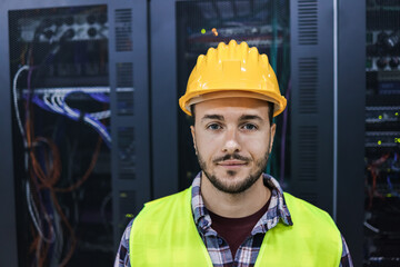 Young technician man looking at camera while working inside big data center room - Focus on face