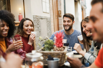 Happy multiracial people having fun drinking coffee outdoor at vintage bar restaurant - Main focus on center man face