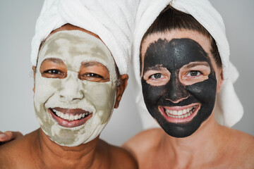 Multiracial senior women doing beauty treatment using skin mask - Body care concept - Focus on right female face