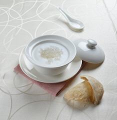 luxury chilled sweet fresh bird nest soup with almond paste and peach resin in bowl and pink table...