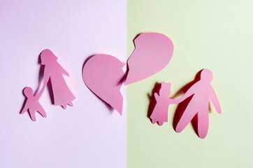 Bright red human figures of people, a large heart divided into two parts on a colored background. The concept of the crisis of family relations. Cardboard figures of adults and children close-up