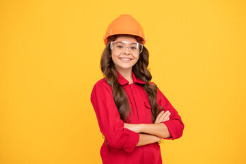 cheerful teen girl wear eyeglasses and helmet. kid future engineer on yellow background.