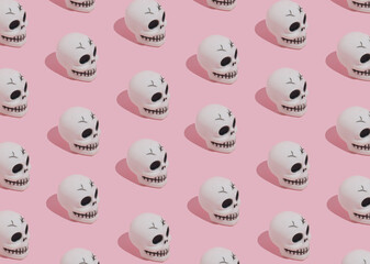 Halloween pattern made of skulls on pink background. Minimal Halloween concept.