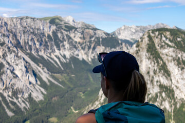 A woman with a hiking backpack admiring the view on the Alpine mountain chains in Austria, Hochschwab region. The slopes are partially overgrown with small bushes, higher parts baren. Happiness