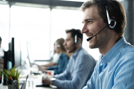 Young handsome male customer support phone operator with headset working in call center