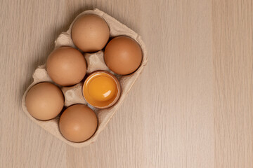 Eggs in eco egg box and whisk on yellow background. Flat lay. Top view. Copy space.