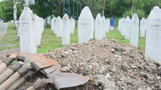 Memorial centre Srebrenica Potocari. Srebrenica Genocide victims' burial. Dirt pile and shovels next to grave in cemetery. 