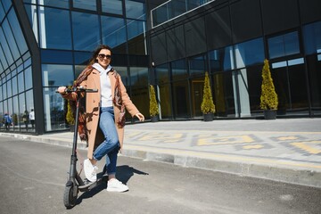 Young beautiful woman riding an electric scooter to work, modern girl, new generation, electric transport, ecology, ecological transport, sunset