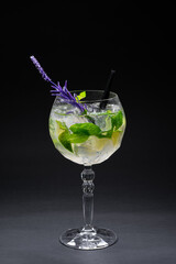 cocktail hugo or mojito with mint, lime and ice in wineglass on black background
