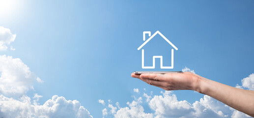 Naklejka premium Male hand holding house icon on blue background. Property insurance and security concept.Real estate concept.Banner with copy space.