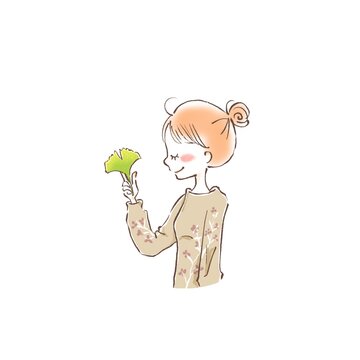 a young woman closing her yes and holding a autumn leave between her fingers
