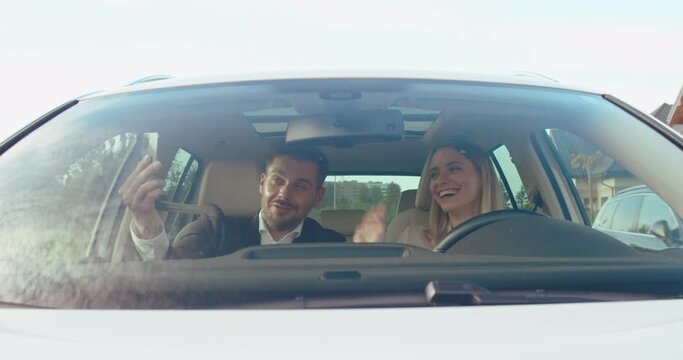 Lets make a selfie. Front view of the caucasian man holding smartphone and making a selfie with his wife or chatting via video call with somebody while riding at the car. People and transport concept