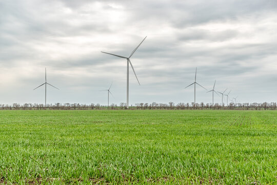 Wind Turbines Generating Electricity In A Green Field. Green Power Generation Concept.