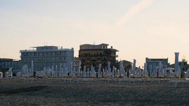 An empty beach with closed sunshades and deck chairs in Caorle, Veneto, Italy. No tourists at the Italian beach due to travel restrictions during the Covid-19, Coronavirus pandemic. 4K.