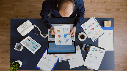 Fototapeta na wymiar Top view of businessman analyzing management graphs documents brainstorming company strategy ideas working in business startup office. Manager sitting at desk planning corporate investment