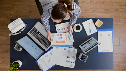 Top view of businesswoman sitting at desk table checking financial accounting documents brainstorming management ideas. Manager working at company investment in startup corporate office