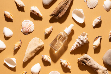 Cosmetic and travel concept with serum bottle and natural matireal with seashell, stone and wood