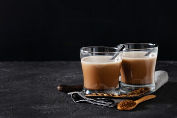 Carob drinks in glass with carob beans on darck and black background
