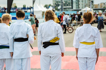 Teenagers in kimonos lined up before the start of the competition. Unrecognizable person. Back view