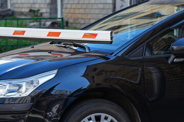 An automatic barrier fell on the hood of a black car. Close-up
