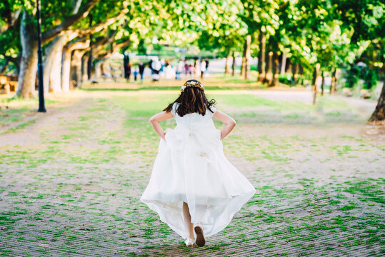 Girl In Communion Dress Running On The Park.