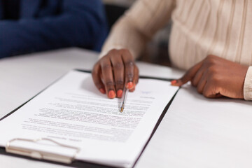 African businesswoman reading signing documents its while business partners sharing paperwork. Executive director meeting shareholders in start up office, making satisfactorily agreement.