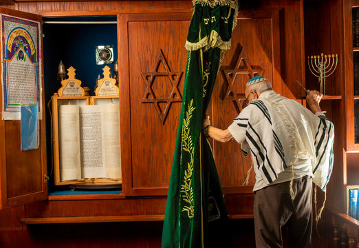an older jewish man in front of  a bible scroll in a synagogue
