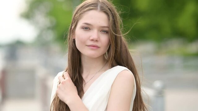 Portrait of Young beautiful brunette girl in dress outdoors. Beautiful happy model girl enjoying nature. 4K UHD