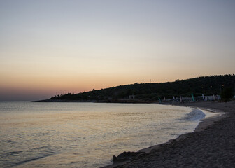 Sunbeds and umbrellas in a distant on the beach, sunset, peaceful nature, calm water, beautiful seascape, travel destination, summer vacation
