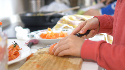 Close-up of children's hands cutting tomatoes. Concept of family cooking. Selective focus.