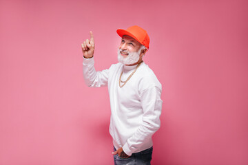 Handsome man in orange cap pointing up on isolated background. Attractive guy with grey beard in...