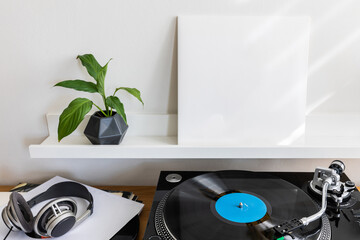 Musical theme mockup with vinyl record turntable player, blank square paper cardbox of Lp cover and big headphones on the table