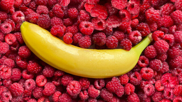 Banana in raspberries, the taste of banana with raspberries, berry background, sex education, background for advertising vibrators, background for diet ads, fruit and berry combination
