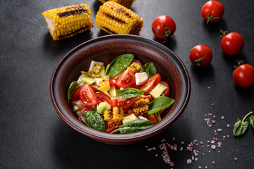 Delicious fresh salad with tomatoes, avocado, cheese and grilled corn with olive oil