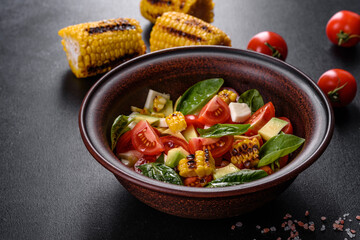 Delicious fresh salad with tomatoes, avocado, cheese and grilled corn with olive oil