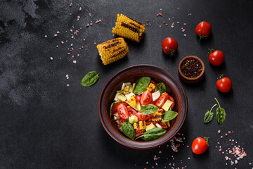 Delicious fresh salad with tomatoes, avocado, cheese and grilled corn with olive oil