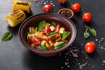Delicious fresh salad with tomatoes, avocado, cheese and grilled corn with olive oil