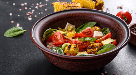 Delicious fresh salad with tomatoes, avocado, cheese and grilled corn with olive oil
