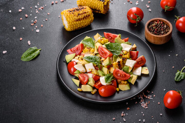 Fototapeta na wymiar Delicious fresh salad with tomatoes, avocado, cheese and grilled corn with olive oil