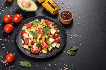 Delicious fresh salad with tomatoes, avocado, cheese and grilled corn with olive oil