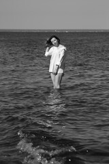 Fototapeta premium Portrait of a woman in white shirt in the sea in black and white