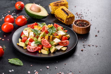 Delicious fresh salad with tomatoes, avocado, cheese and grilled corn with olive oil