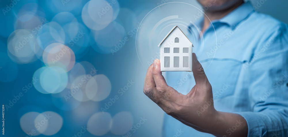 Poster man's hand holding small house model with auto home innovation icons on virtual screen. smart home c