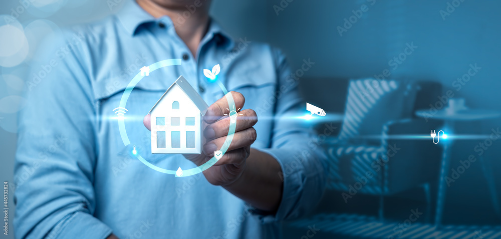 Aufkleber man's hand holding small house model with auto home innovation icons on virtual screen. smart home c