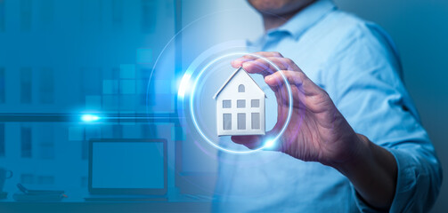 Man's hand holding small house model with auto home innovation icons on virtual screen. Smart home...